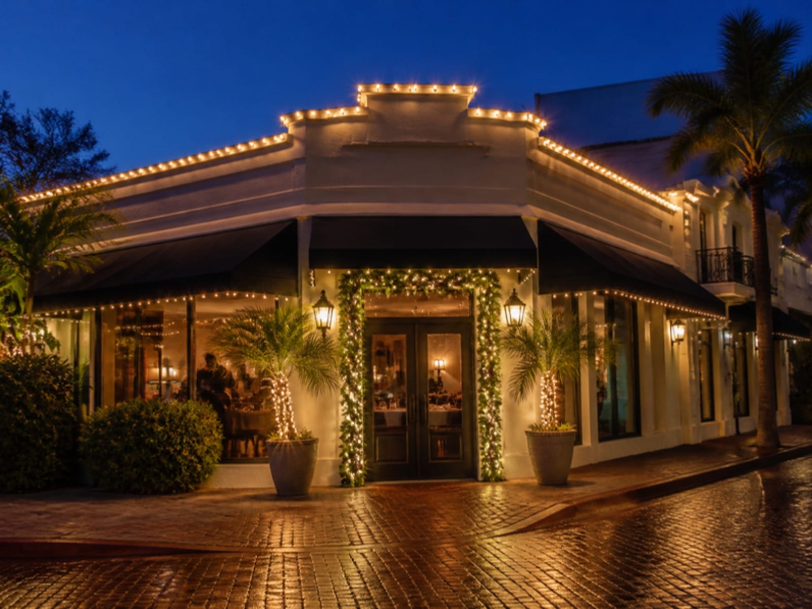 Concept: a restaurant storefront with warm-white lights along the parapet and garland at the entry